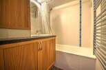 This charming bathroom boasts a sleek, modern design with wood-paneled cabinetry and a bathtub.