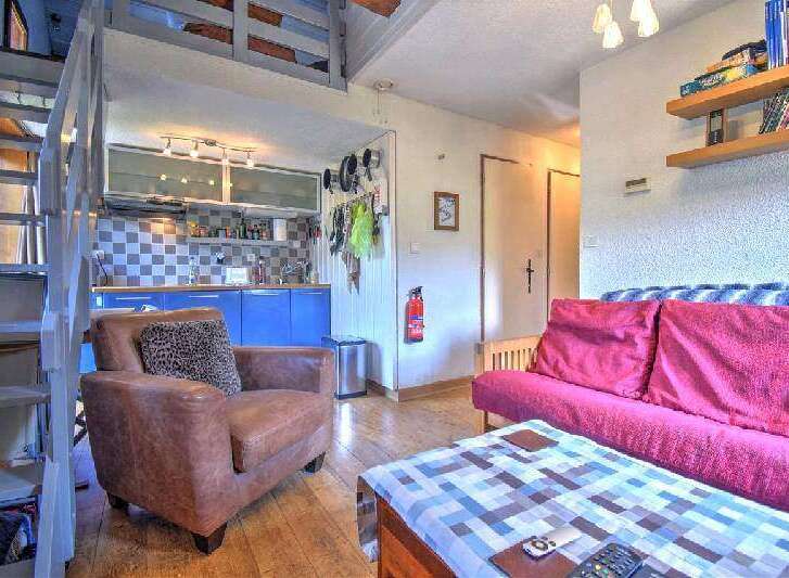 Cozy studio apartment featuring a loft bedroom, fully equipped kitchenette, and comfortable living area with a sofa bed.