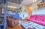 Cozy studio apartment featuring a loft bedroom, fully equipped kitchenette, and comfortable living area with a sofa bed.