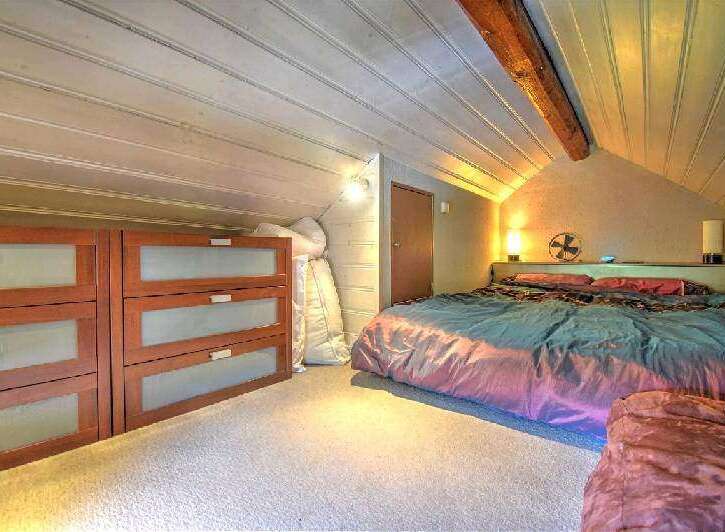 Cozy attic bedroom with wooden beams and ample storage.