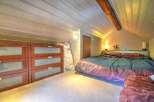 Cozy attic bedroom with wooden beams and ample storage.