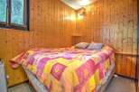 Cozy cabin room with wood paneling and a comfortable bed.