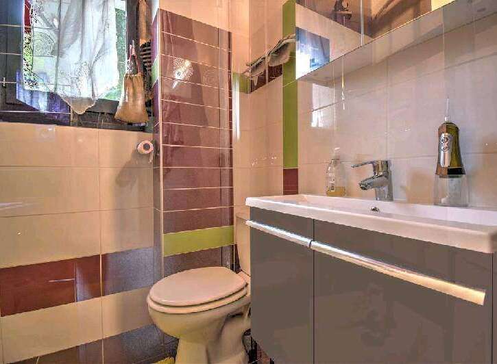This charming bathroom boasts a modern sink and vanity, complemented by stylish tiled walls.