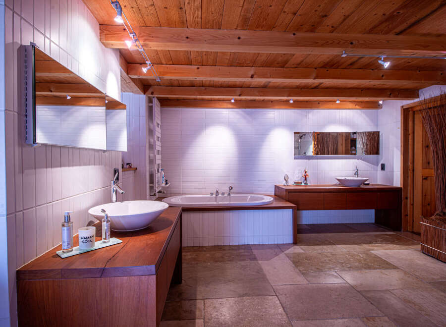 Luxurious bathroom with wooden beams and tiled walls.