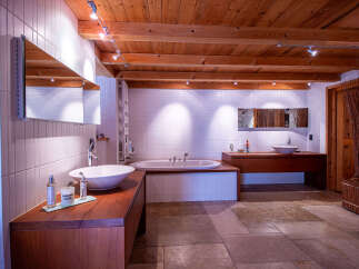 Luxurious bathroom with wooden beams and tiled walls.
