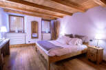 Cozy chalet bedroom with wooden beams, hardwood floors, and a comfortable bed.