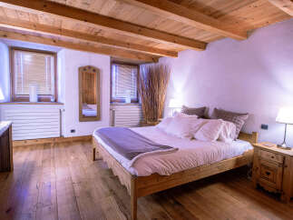 Cozy chalet bedroom with wooden beams, hardwood floors, and a comfortable bed.