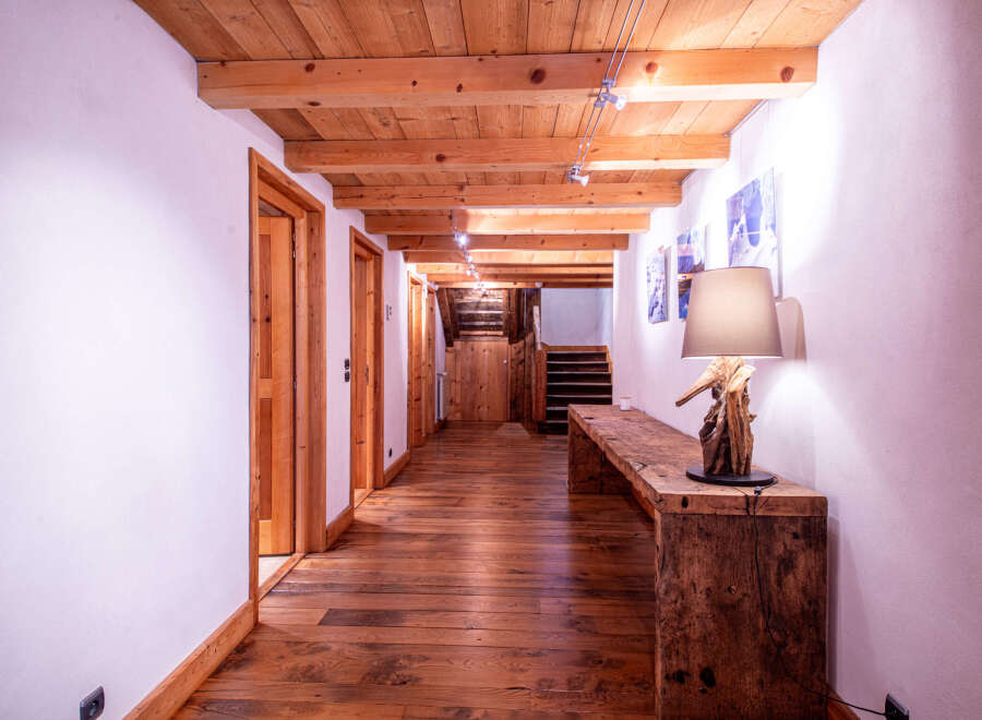 This stunning hallway boasts a rustic-chic design with exposed wooden beams, hardwood floors, and charming wooden doors.