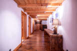 This stunning hallway boasts a rustic-chic design with exposed wooden beams, hardwood floors, and charming wooden doors.