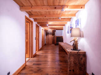 This stunning hallway boasts a rustic-chic design with exposed wooden beams, hardwood floors, and charming wooden doors.