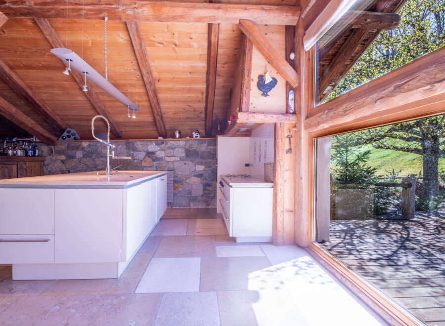 This stunning chalet boasts a modern kitchen with white cabinetry and a large island, seamlessly blending contemporary design with rustic charm.