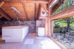 This stunning chalet boasts a modern kitchen with white cabinetry and a large island, seamlessly blending contemporary design with rustic charm.