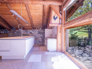 This stunning chalet boasts a modern kitchen with white cabinetry and a large island, seamlessly blending contemporary design with rustic charm.