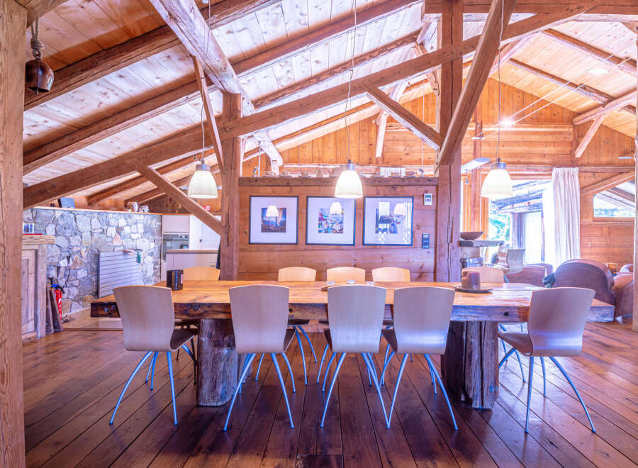 Rustic mountain chalet with exposed wooden beams and a large dining table.