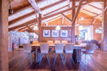 Rustic mountain chalet with exposed wooden beams and a large dining table.