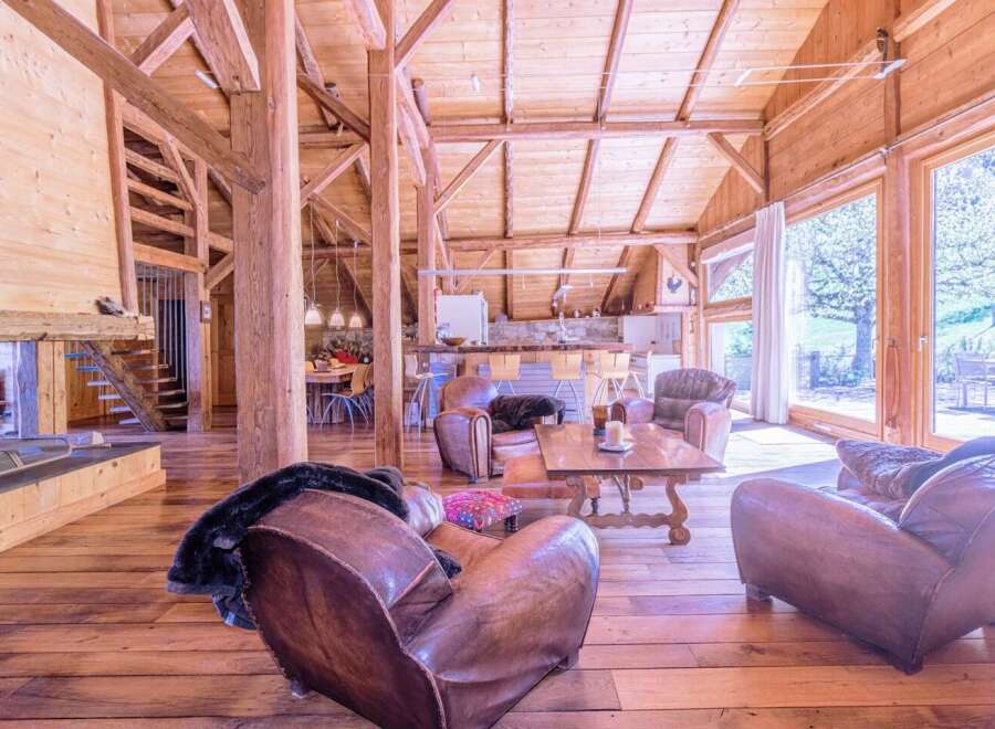 This stunning chalet boasts a spacious open-plan living area with exposed wooden beams and large windows offering breathtaking views.