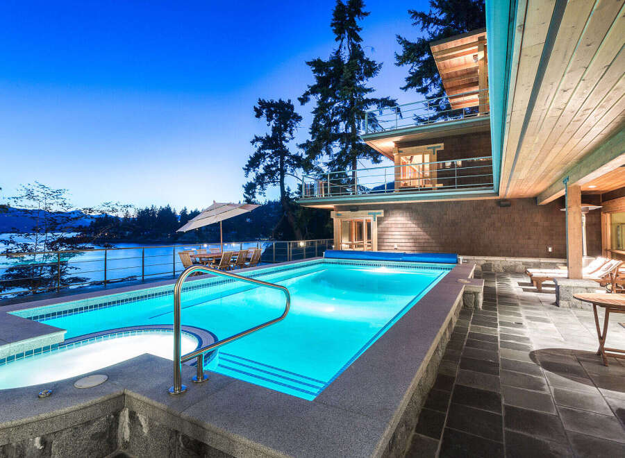 Luxury waterfront property featuring a stunning infinity pool and hot tub, perfect for enjoying breathtaking sunset views.