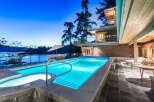Luxury waterfront property featuring a stunning infinity pool and hot tub, perfect for enjoying breathtaking sunset views.