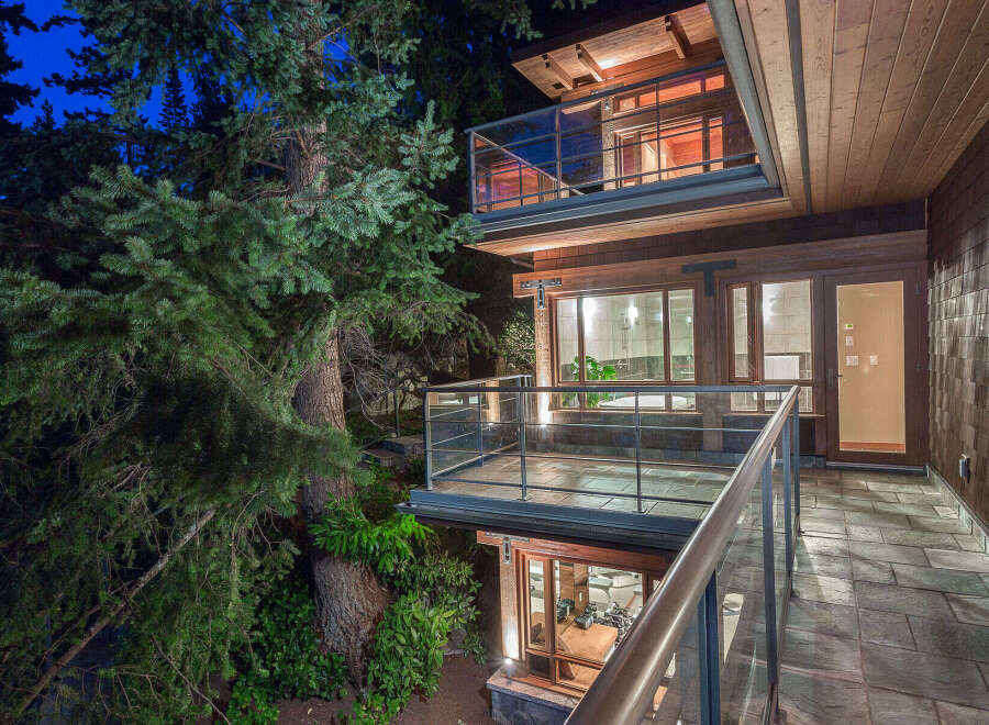 This stunning home boasts a multi-level design with expansive decks and balconies, offering breathtaking views of the surrounding lush forest.