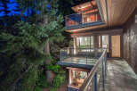 This stunning home boasts a multi-level design with expansive decks and balconies, offering breathtaking views of the surrounding lush forest.