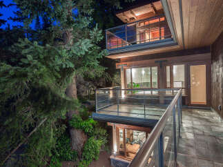 This stunning home boasts a multi-level design with expansive decks and balconies, offering breathtaking views of the surrounding lush forest.