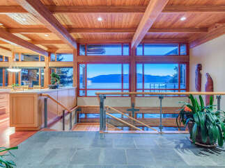 This stunning home boasts a breathtaking view of the water and mountains, visible through expansive windows.