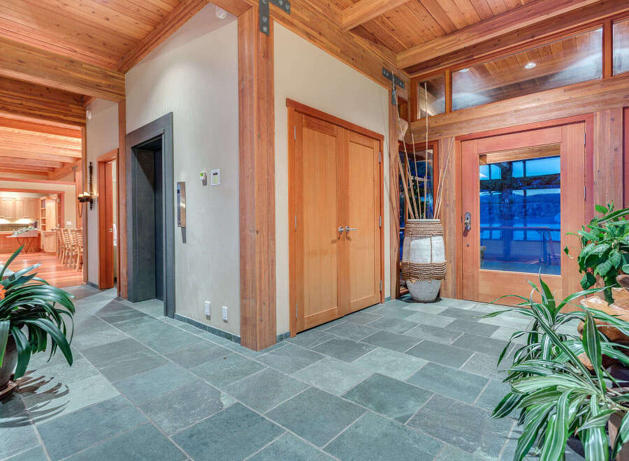 This stunning foyer boasts a spacious and bright design, featuring a beautiful slate tile floor and wood-beamed ceiling.
