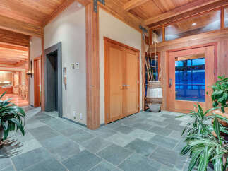 This stunning foyer boasts a spacious and bright design, featuring a beautiful slate tile floor and wood-beamed ceiling.