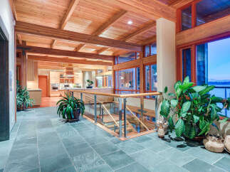 This stunning home boasts a spacious open floor plan with high ceilings, exposed wooden beams, and large windows offering breathtaking water views.