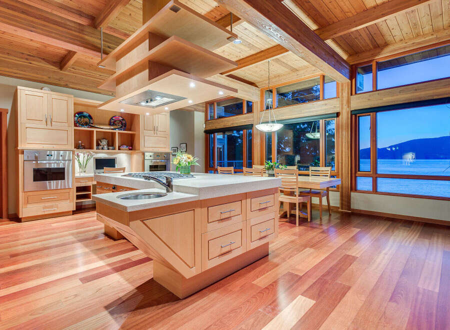 This stunning kitchen boasts a unique wooden ceiling and large windows offering breathtaking water views.