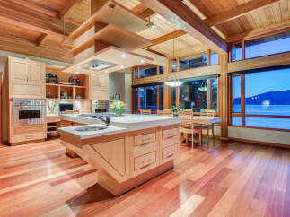 This stunning kitchen boasts a unique wooden ceiling and large windows offering breathtaking water views.