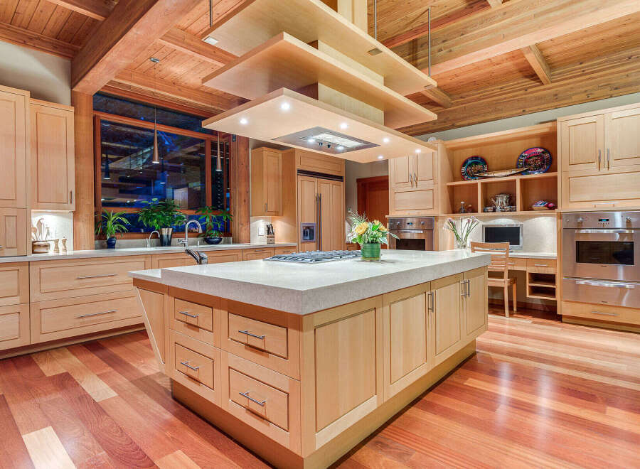 This stunning kitchen boasts a large island with ample storage, a high-end range, and a built-in desk area.