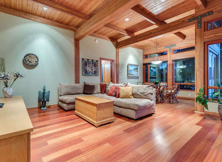 This stunning home boasts a spacious living area with hardwood floors, a cozy sectional sofa, and a wood-paneled ceiling.