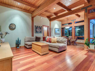 This stunning home boasts a spacious living area with hardwood floors, a cozy sectional sofa, and a wood-paneled ceiling.