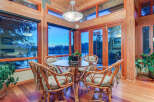 This stunning dining area boasts breathtaking views through expansive windows, showcasing serene waters and lush greenery.