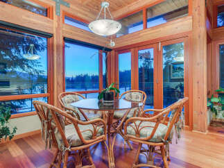 This stunning dining area boasts breathtaking views through expansive windows, showcasing serene waters and lush greenery.