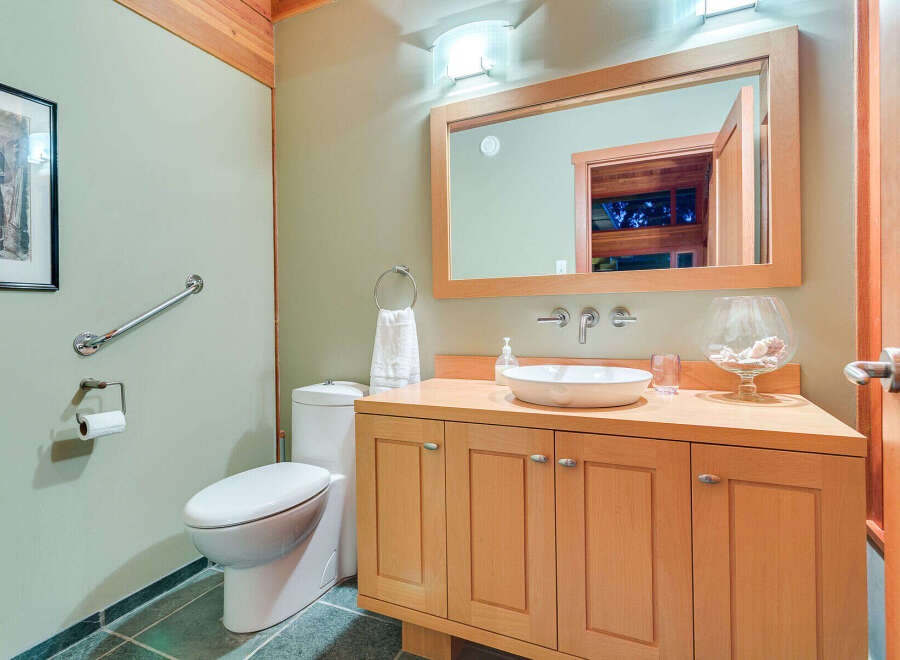 This stunning bathroom boasts a light and airy feel, with soft green walls and light wood cabinetry.