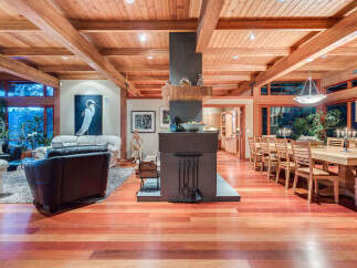 This stunning home boasts a spacious open floor plan with hardwood floors, high ceilings with exposed beams, and large windows offering abundant natural light.