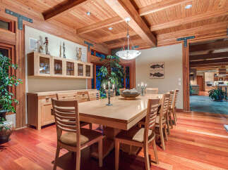This stunning dining room boasts a large, light-wood table surrounded by comfortable chairs, perfect for family gatherings.