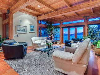 This stunning waterfront property boasts a spacious living area with floor-to-ceiling windows offering breathtaking views.