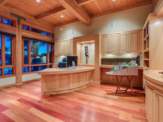 This stunning home office boasts a curved wooden desk, built-in bookshelves, and large windows offering breathtaking views.