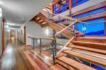 This stunning home boasts a grand wooden staircase with glass railings, offering breathtaking views through expansive windows.