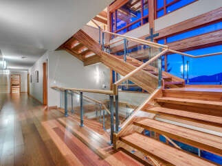 This stunning home boasts a grand wooden staircase with glass railings, offering breathtaking views through expansive windows.