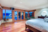 This luxurious bedroom boasts stunning lake views from its wall-to-wall windows and glass doors, creating a bright and airy atmosphere.