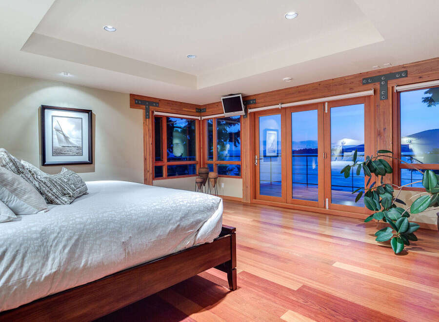 This luxurious bedroom boasts stunning ocean views from its large windows and patio doors, creating a serene and relaxing atmosphere.