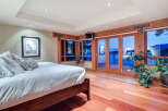 This luxurious bedroom boasts stunning ocean views from its large windows and patio doors, creating a serene and relaxing atmosphere.