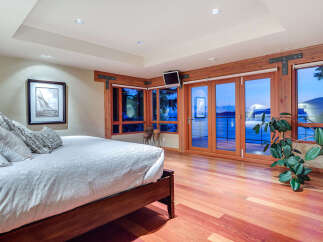 This luxurious bedroom boasts stunning ocean views from its large windows and patio doors, creating a serene and relaxing atmosphere.
