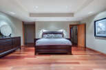 This luxurious bedroom boasts a king-size bed with plush bedding, complemented by hardwood floors and recessed lighting.