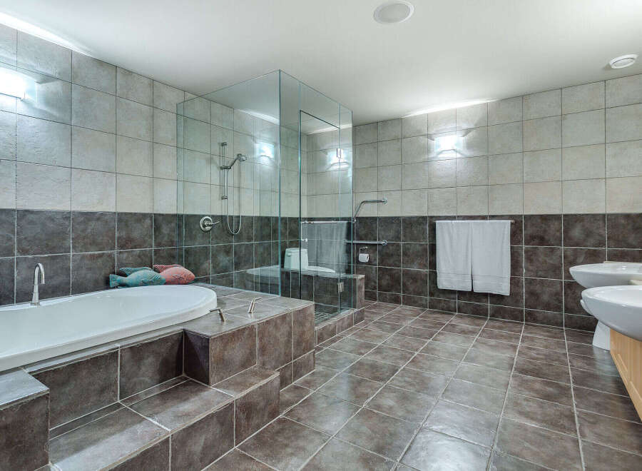 This luxurious bathroom boasts a spacious design with a large soaking tub, a walk-in shower with glass enclosure, and double sinks.