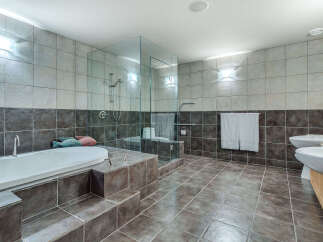 This luxurious bathroom boasts a spacious design with a large soaking tub, a walk-in shower with glass enclosure, and double sinks.
